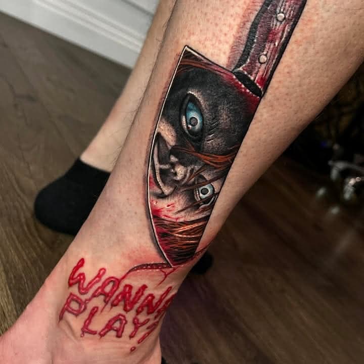 Colour Chucky horror tattoo with a knife and the words Wanna Play by Independence Ink.