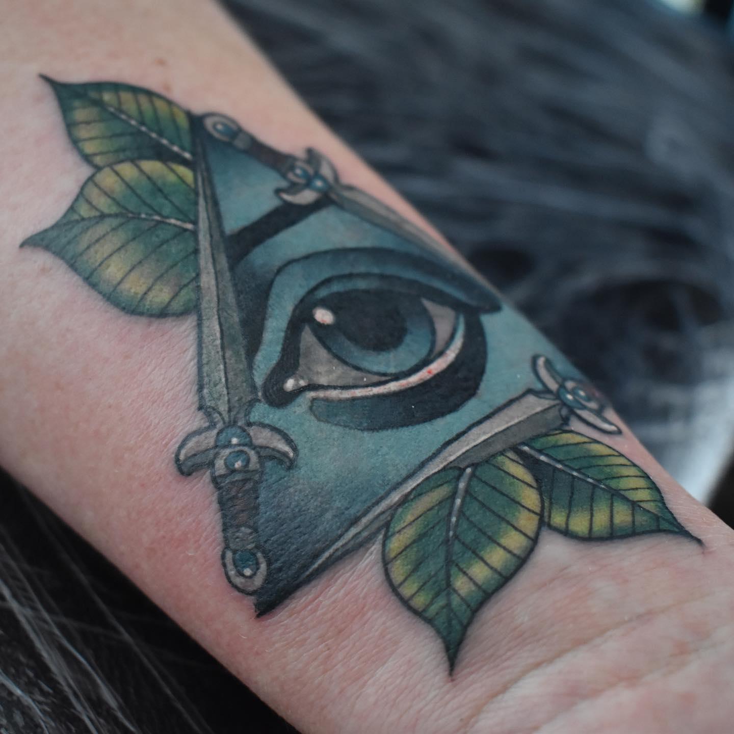 Neo-traditional eye and daggers cover-up tattoo hiding an old faded scorpion on the wrist by Independence Ink.