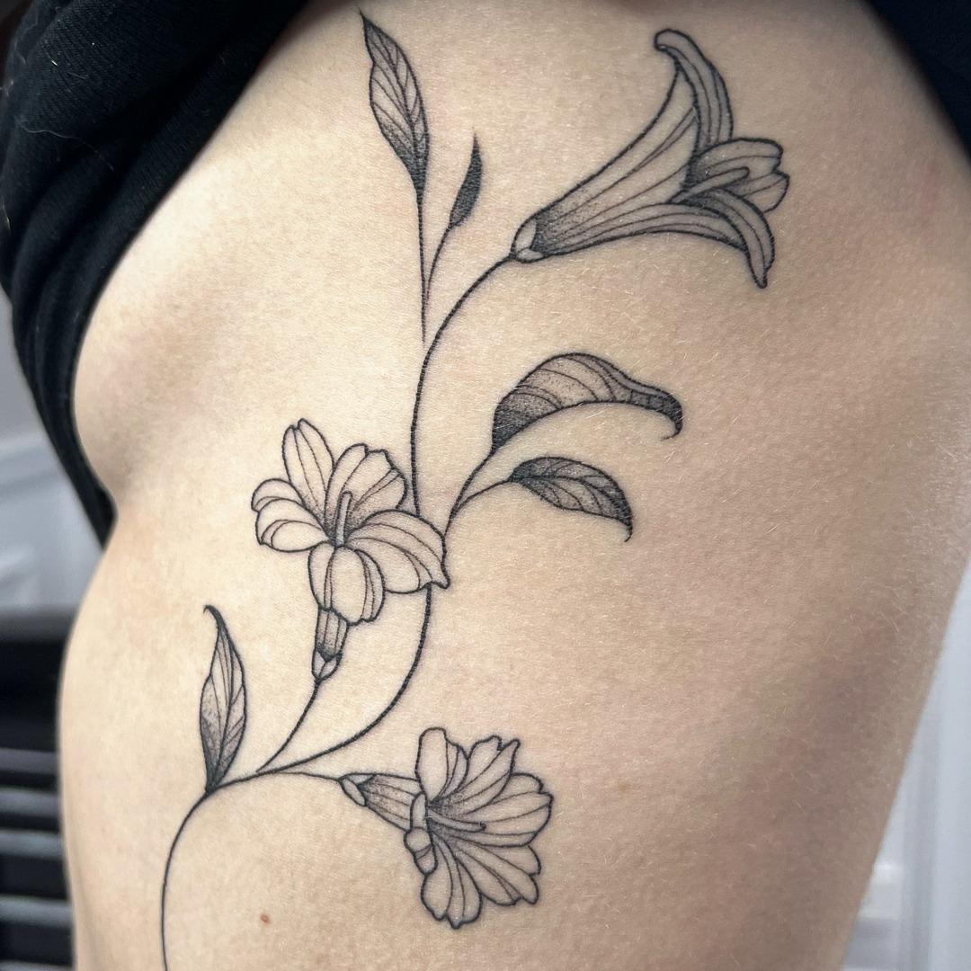 Delicate fine line floral tattoo of lilies along the ribs by Independence Ink.