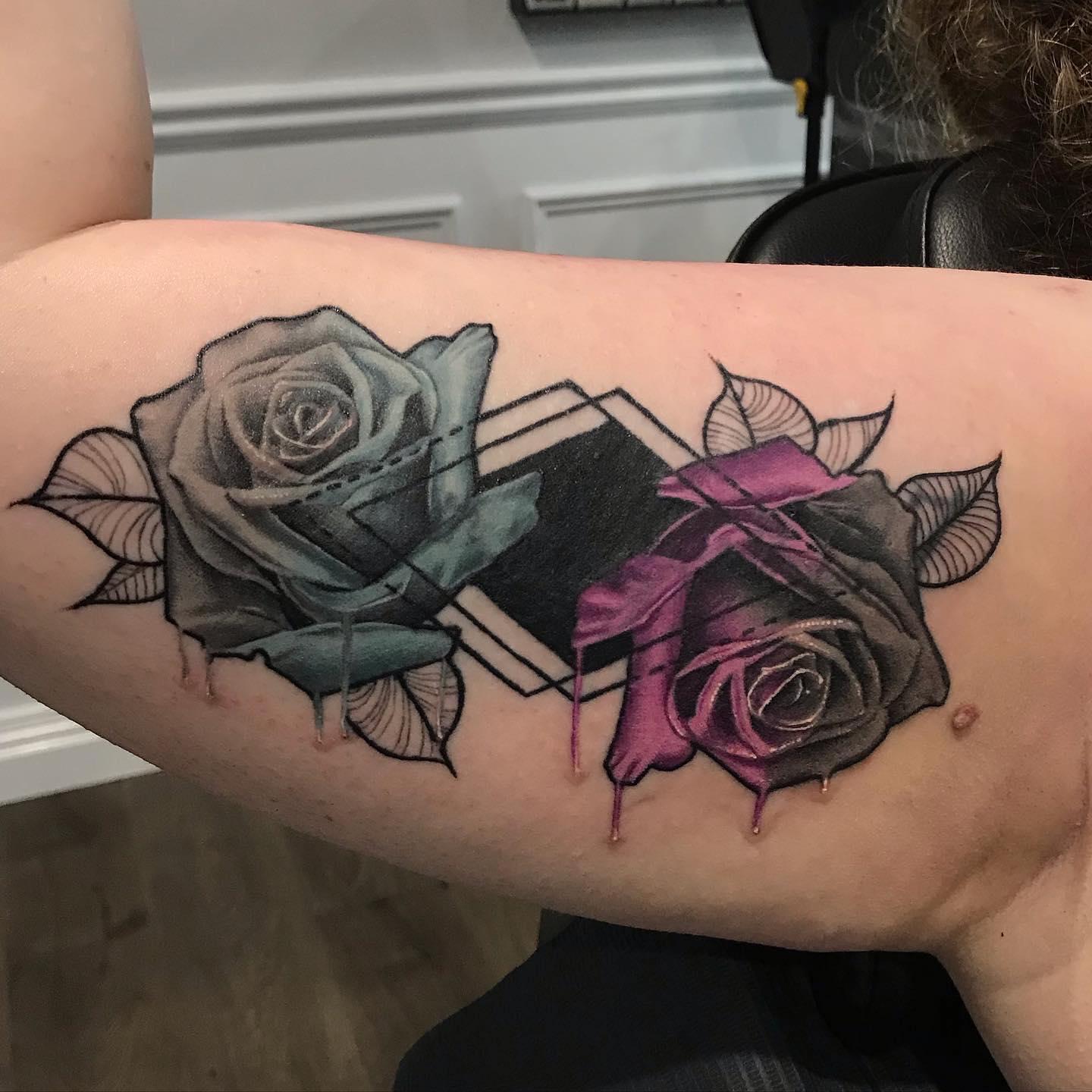Roses and geometric shapes cover-up tattoo over an old script name on the upper arm by Independence Ink.