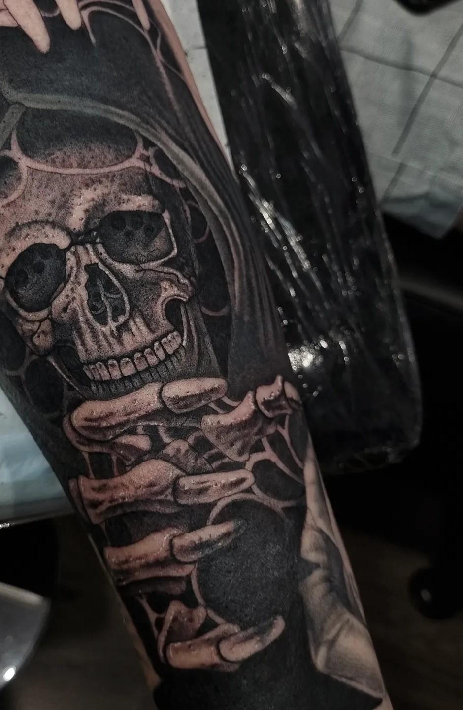 Black and grey grim reaper skull forearm tattoo covering an old Southern Cross tattoo, by Independence Ink in Camden.