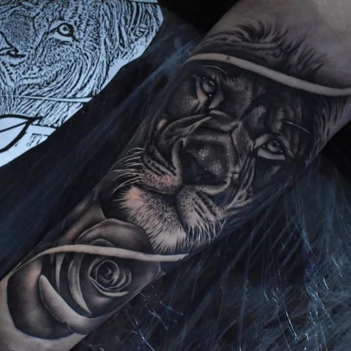 Black and grey realism tattoo of a lion and rose by Independence Ink in Camden.