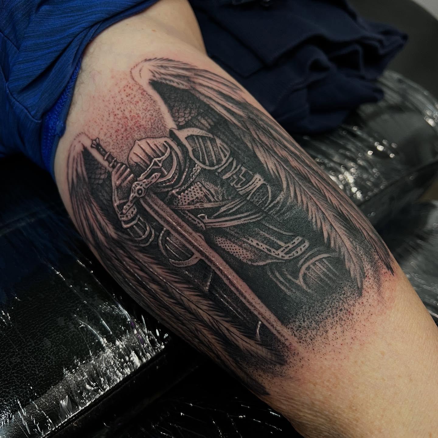 Black and grey tattoo of a winged knight in armour holding a sword by Nicholas.